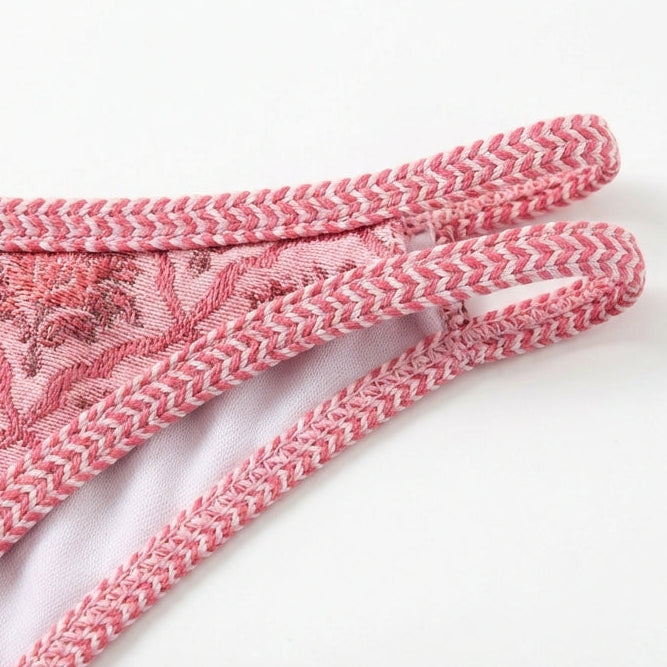 Close-up of pink lace fabric with intricate patterns on a white background